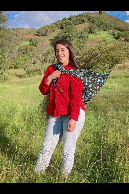 La Fanny con casaca roja sonriendo en el campo cajamarquino